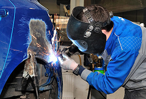 body shop worker welding on a car